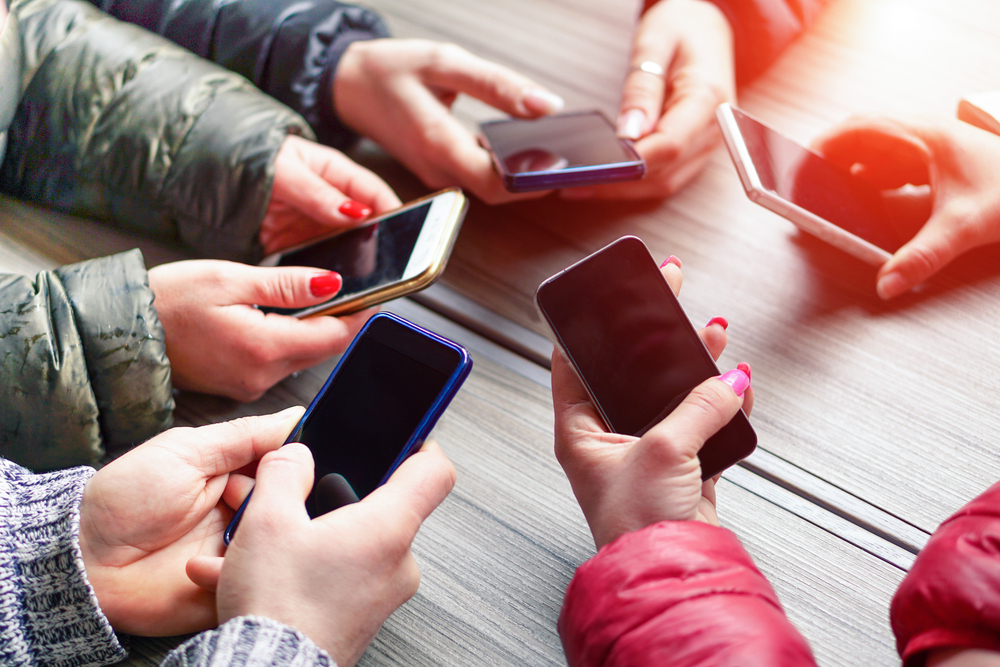 5 personnes autours d'une table avec un téléphone dans la main