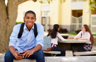 Jeune homme assis sur un banc d'école