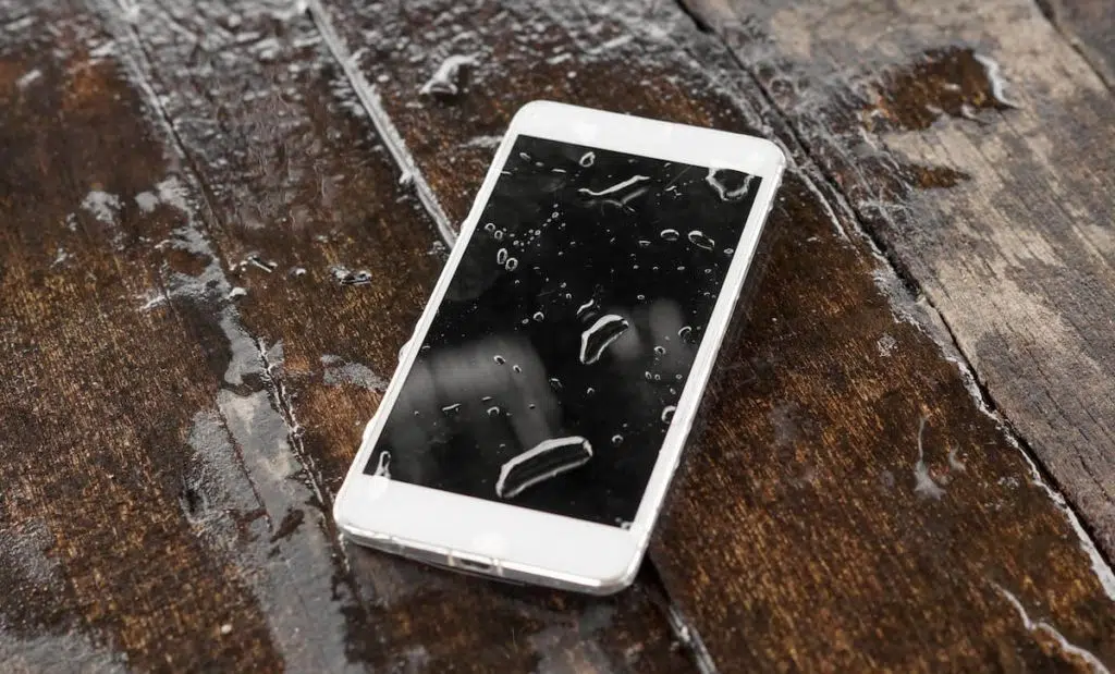 a phone that is lying in a puddle of water with a couple droplets on the screen