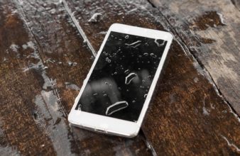 a phone that is lying in a puddle of water with a couple droplets on the screen