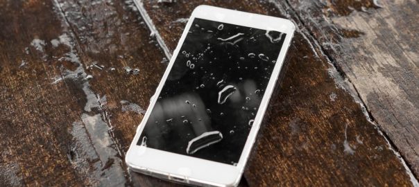 a phone that is lying in a puddle of water with a couple droplets on the screen