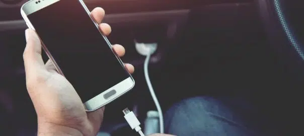 person in a car plugging in an iphone 6 with a white charger