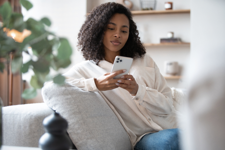young person sitting on a couch looking at phone