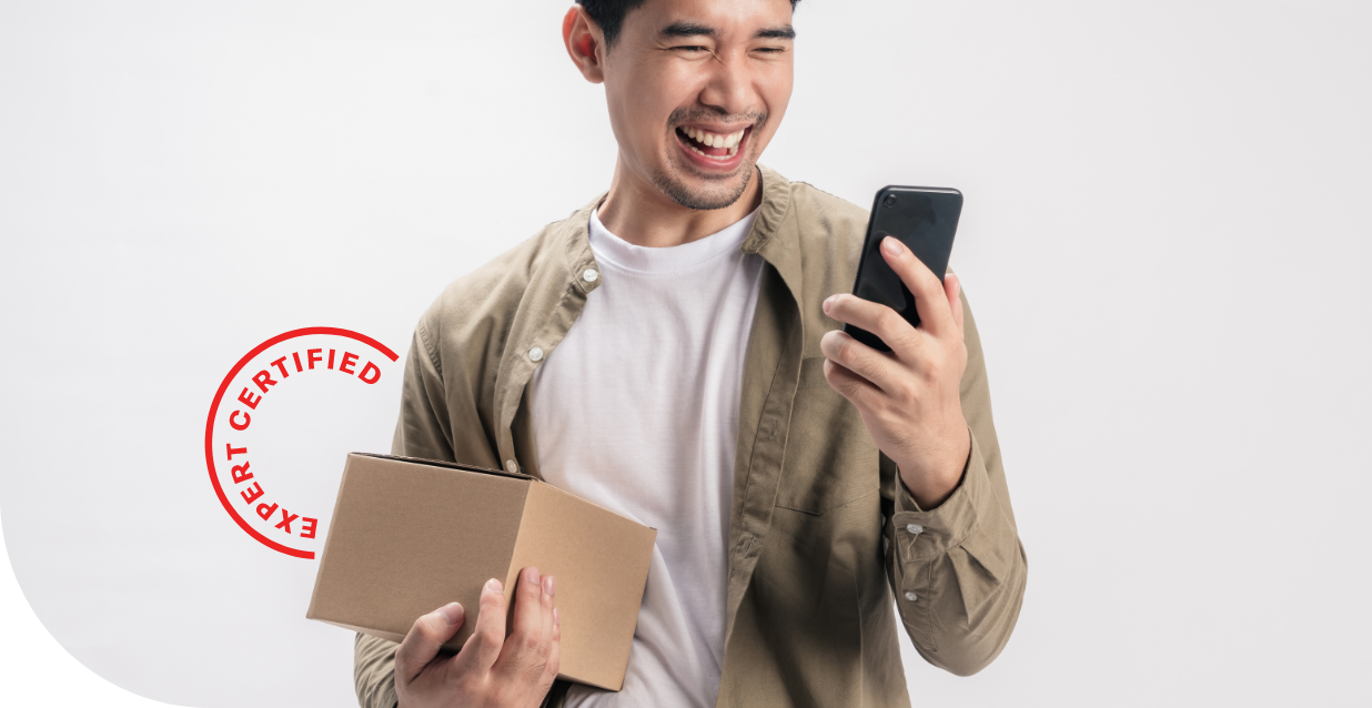 a man holding a box and looking at his phone while smiling