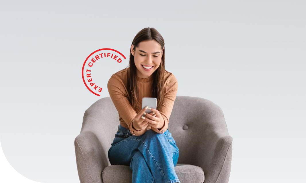 woman sitting in a chair, looking at her phone and smiling