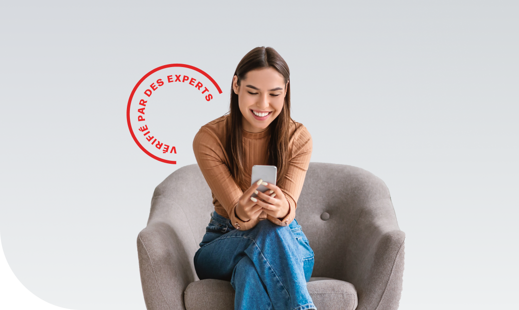 woman sitting in a chair, looking at her phone and smiling
