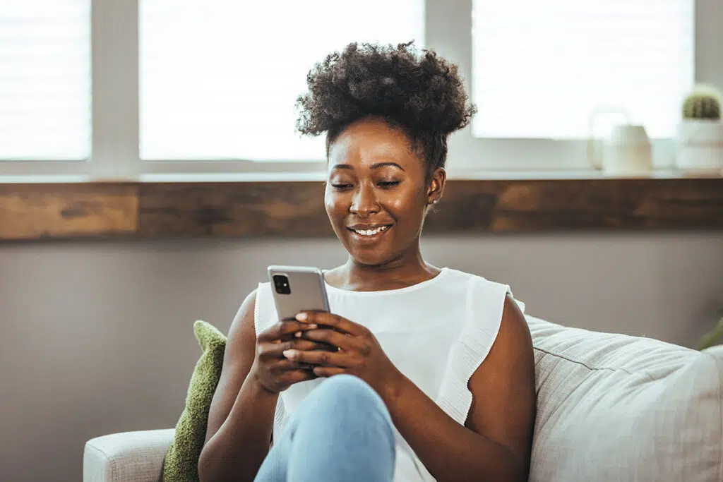A person sitting on a couch and smiling at their phone