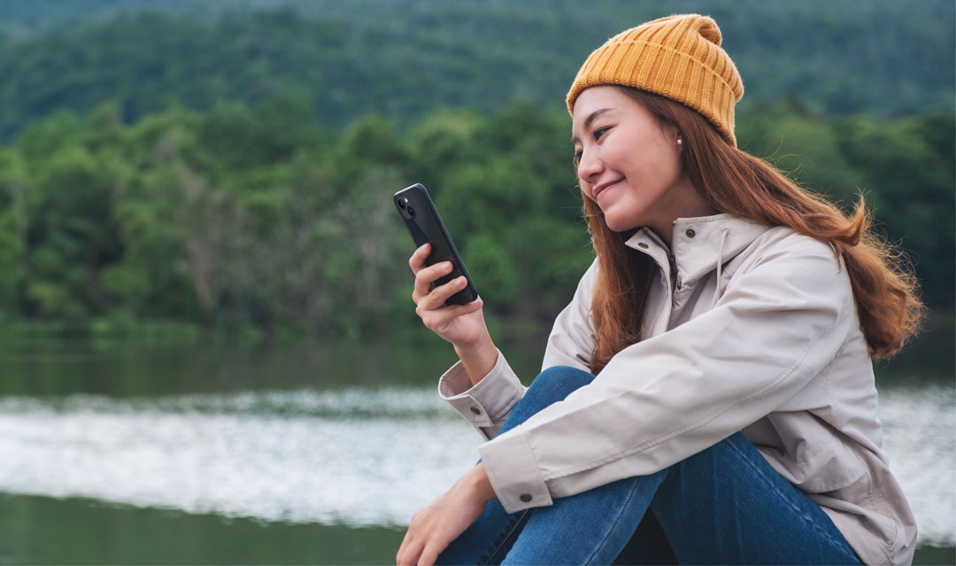 woman looking at phone by a lake